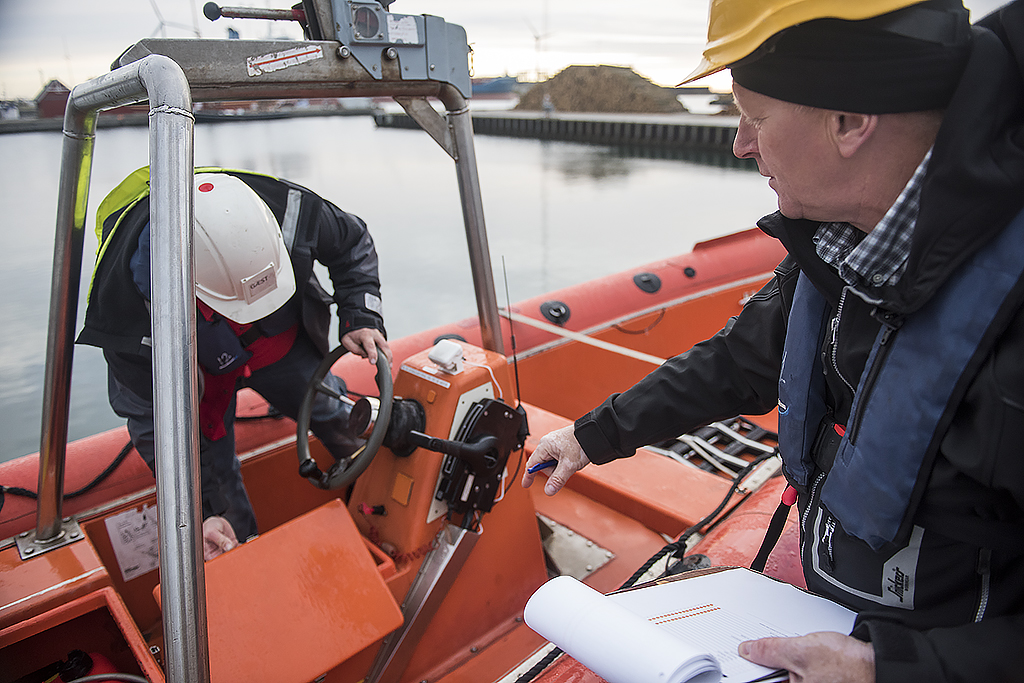 CRALOG technician inspecting a lifeboat with documentation